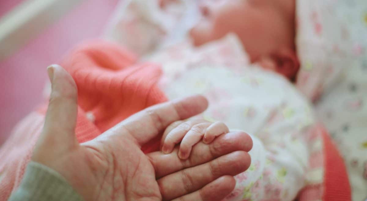 Une mère de famille qui tient la main de son bébé - Source : Getty